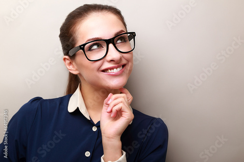 Thinking business woman in glasses looking up