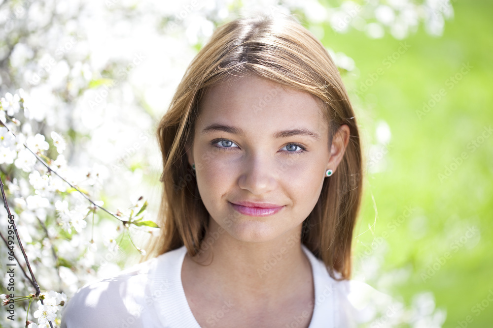 Beautiful young girl standing near blooming trees in spring gard Beautiful young girl standing near blooming trees in spring gard