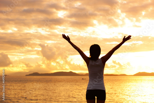 cheering woman open arms at sunrise seaside