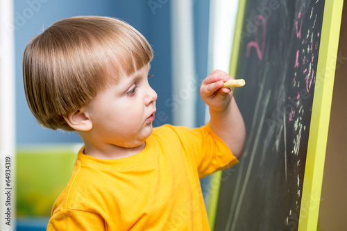 Little boy draws with chalk...