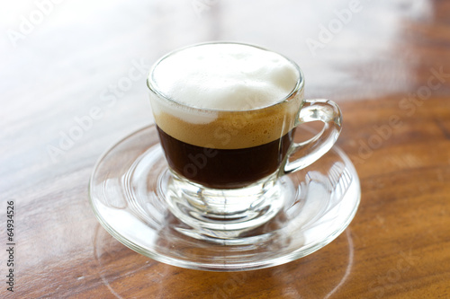 Hot  espresso with milk and foam in cup.