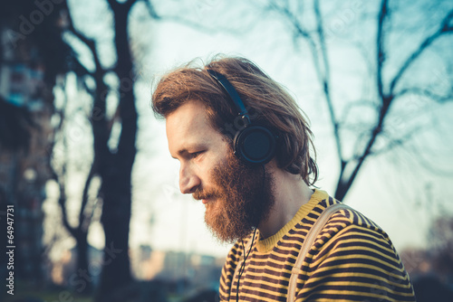 young bearded stylish handsome hipster man listening music