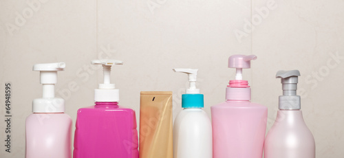 Row of toiletry bottles against bathroom wall