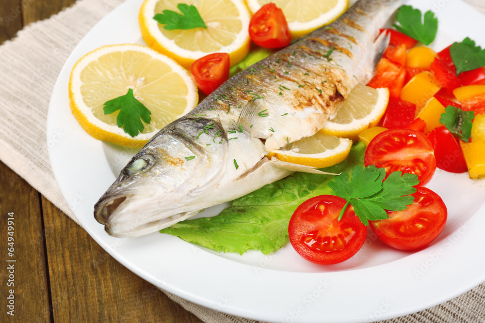 Delicious grilled fish on plate on table close-up Delicious grilled fish on plate on table close-up