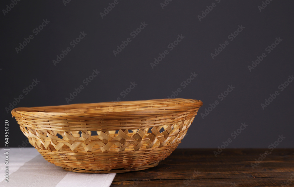 Empty wicker basket on wooden table, on dark background Empty wicker basket on wooden table, on dark background