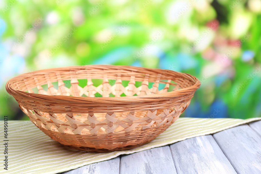 Empty wicker basket on wooden table, on bright background Empty wicker basket on wooden table, on bright background