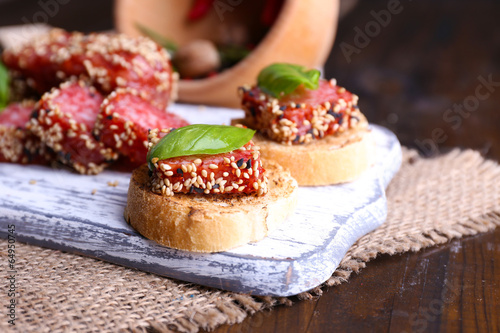 Composition with knife, tasty sandwiches with salami sausage,