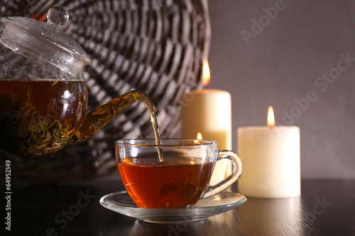 Tea pouring into glass cup on dark background