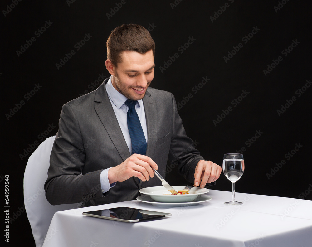 smiling man with tablet pc eating main course smiling man with tablet pc eating main course