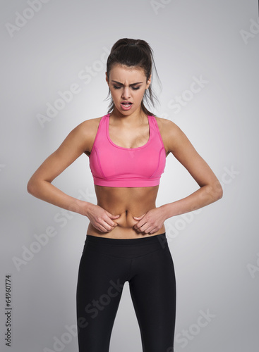 Unhappy young woman pinching belly . © gpointstudio