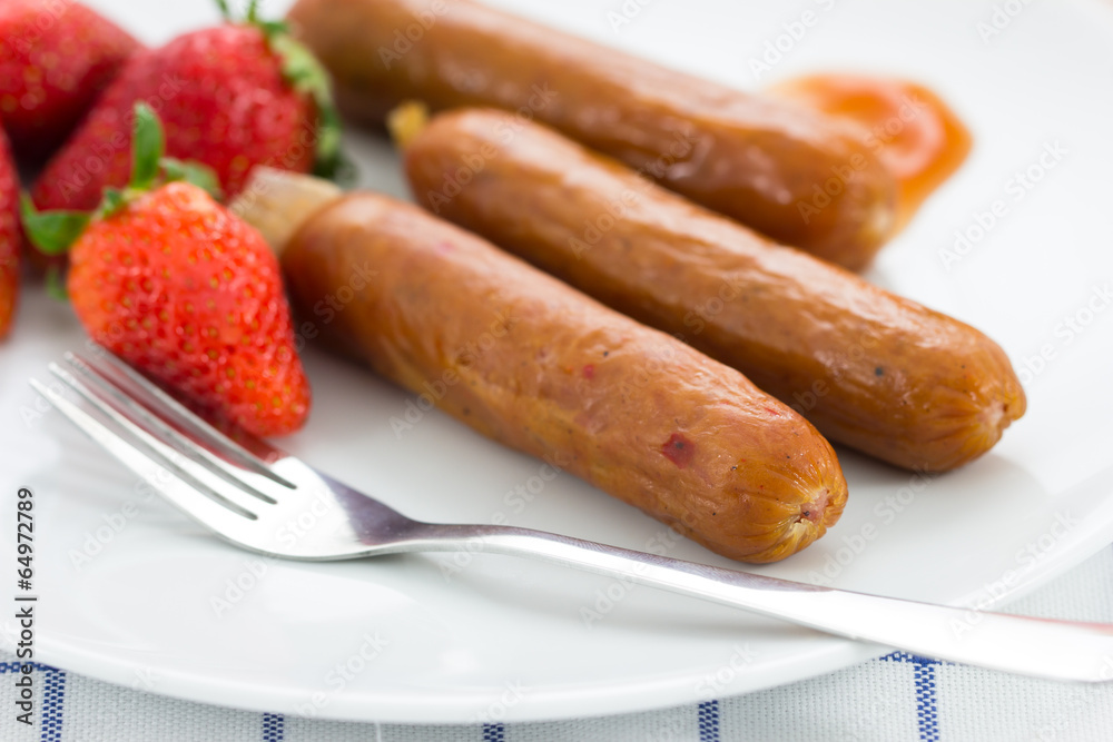 smoked sausage with fresh strawberry on the white plate smoked sausage with fresh strawberry on the white plate