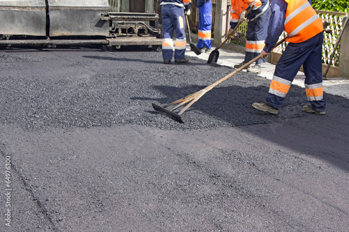 Workers on Asphalting paver machine during Road street repairing works 