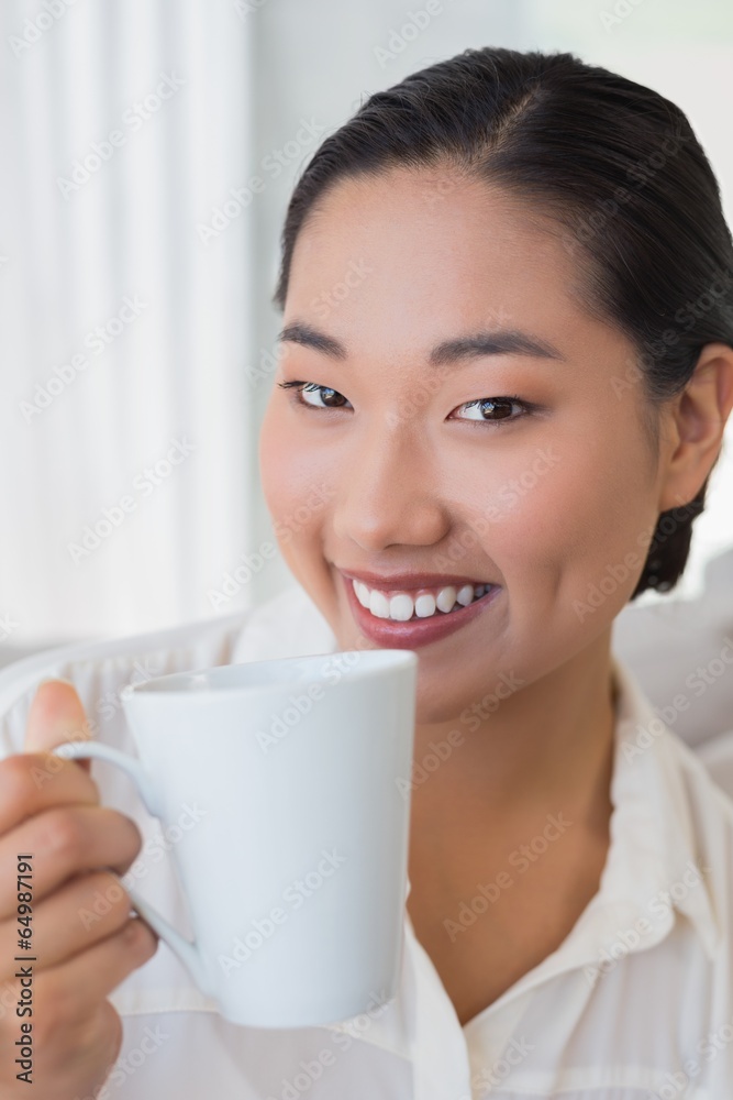 Smiling woman sitting on couch having coffee Smiling woman sitting on couch having coffee