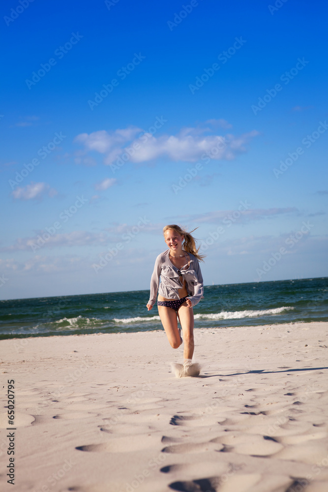 Teenager rennt durch den weißen Sand am Strand