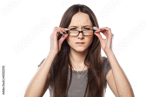 frowning young woman adjust her glasses