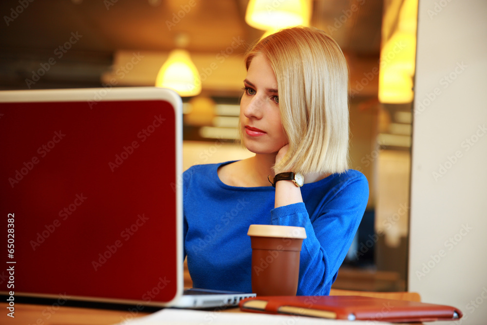 Young beautiful woman sitting at the table with laptop Young beautiful woman sitting at the table with laptop