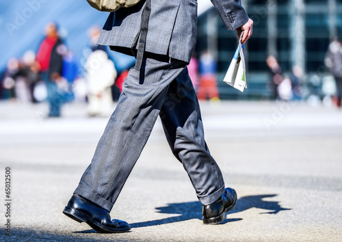 Business traveler man walking with newspaper in the street