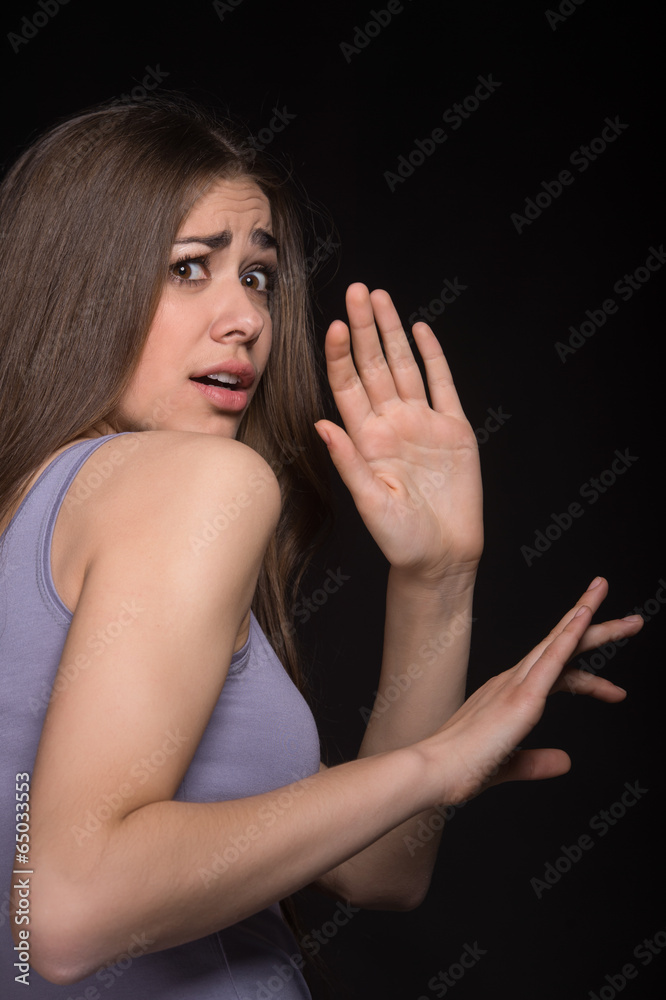 beautiful brunette girl protecting herself on black background.