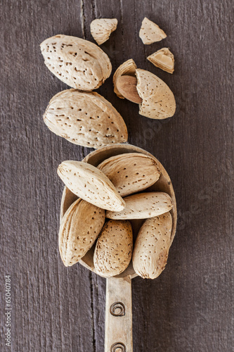 whole and broken almonds on wooden table photo