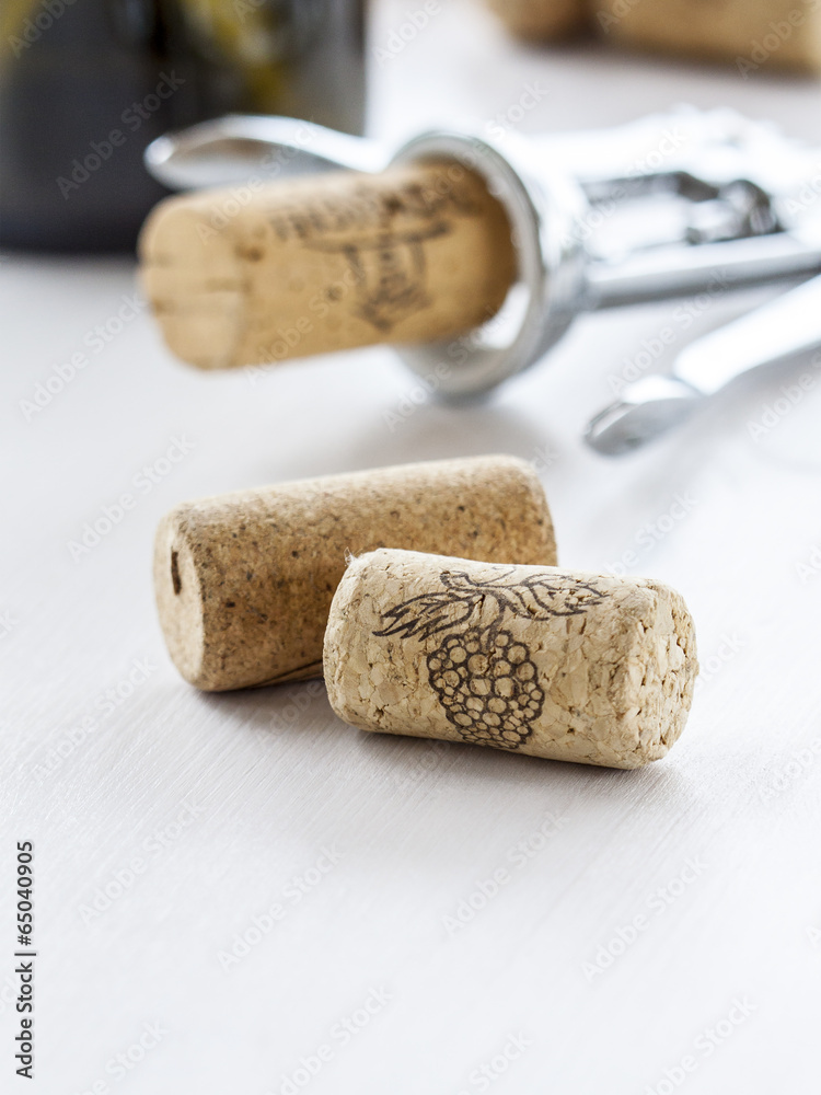 Wine corks and corkscrew next to the bottle of wine.