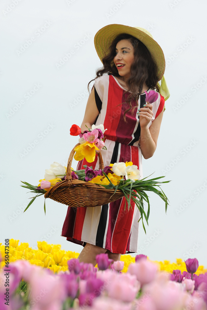 Beautiful hatted girl in tulips with basket