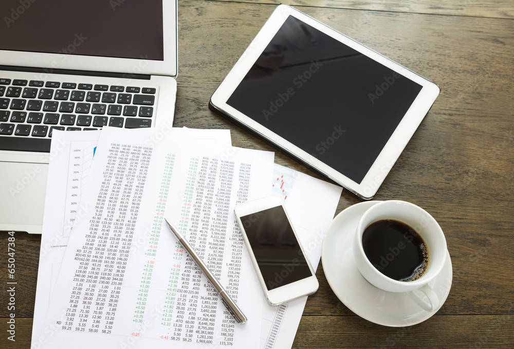 Laptop, tablet , smartphone and coffee cup with financial docum Laptop, tablet , smartphone and coffee cup with financial docum