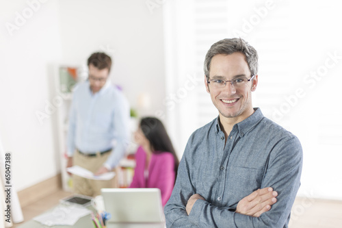 senior businessman standing in front of his colleagues in office