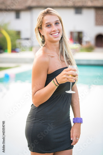 Beautiful Young Woman Drinking next to Swimming Pool