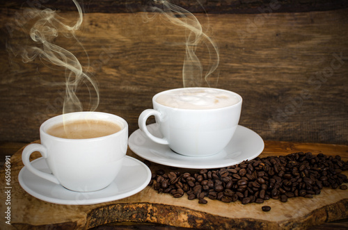 Two cups of cafe latte and coffee beans on old wooden board