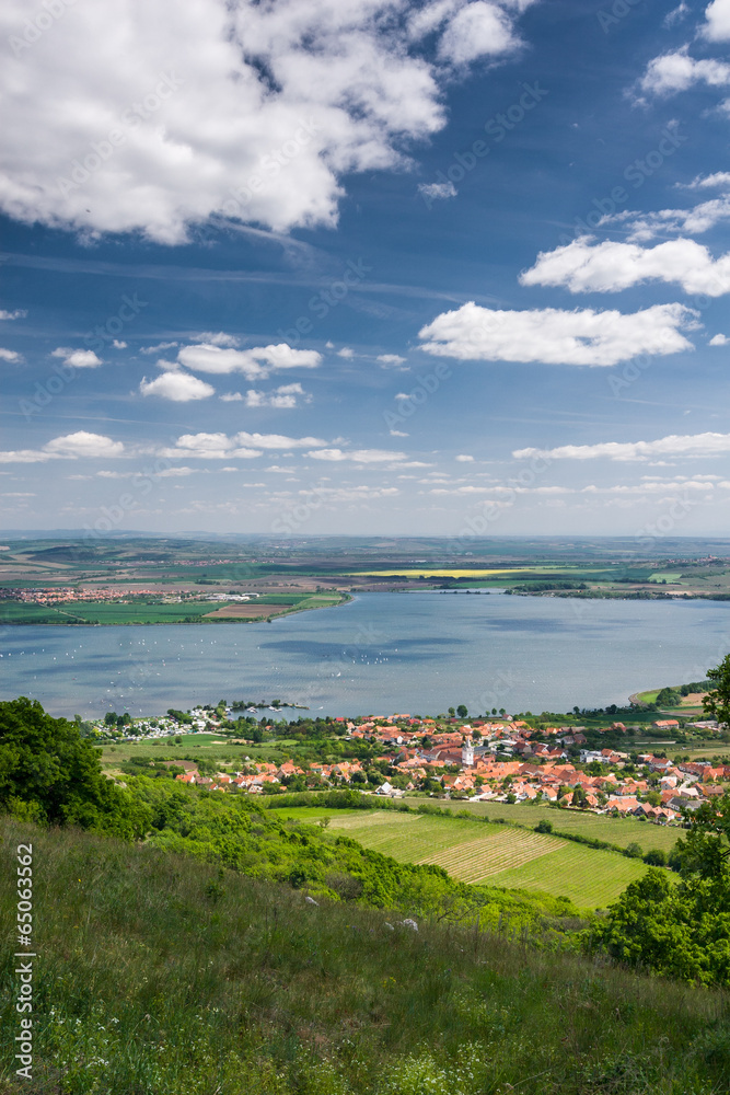 Spring countryside with village, lake, blue sky and clouds