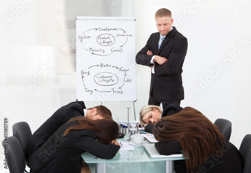 Businessman Looking At Colleagues Sleeping During Presentation photo