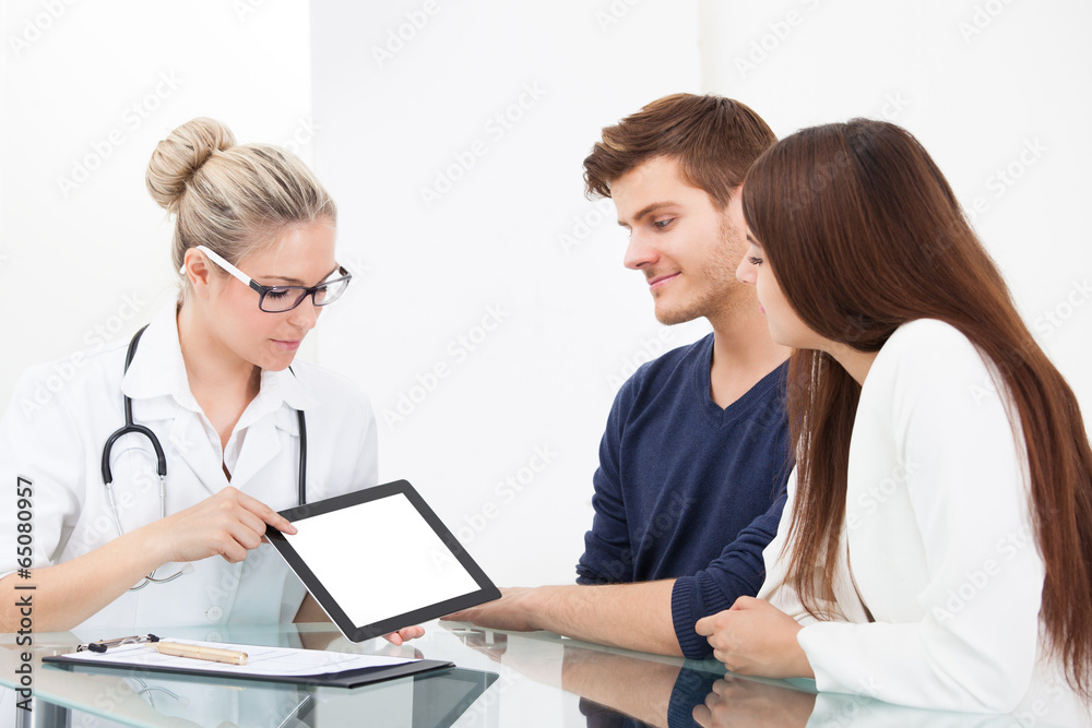 Doctor Showing Report To Couple On Digital Tablet Doctor Showing Report To Couple On Digital Tablet