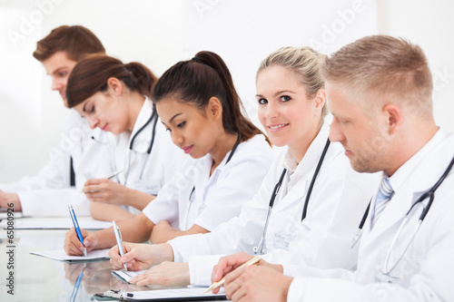 Row Of Doctors Writing At Desk