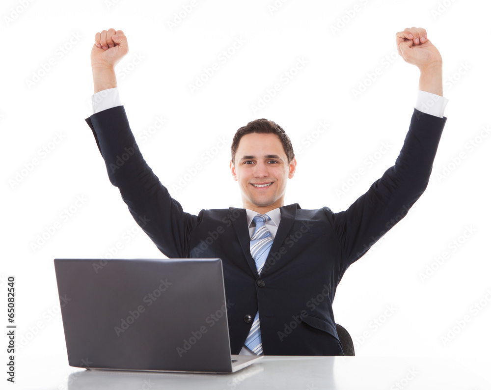 Smiling Businessman Celebrating Success At Desk Smiling Businessman Celebrating Success At Desk