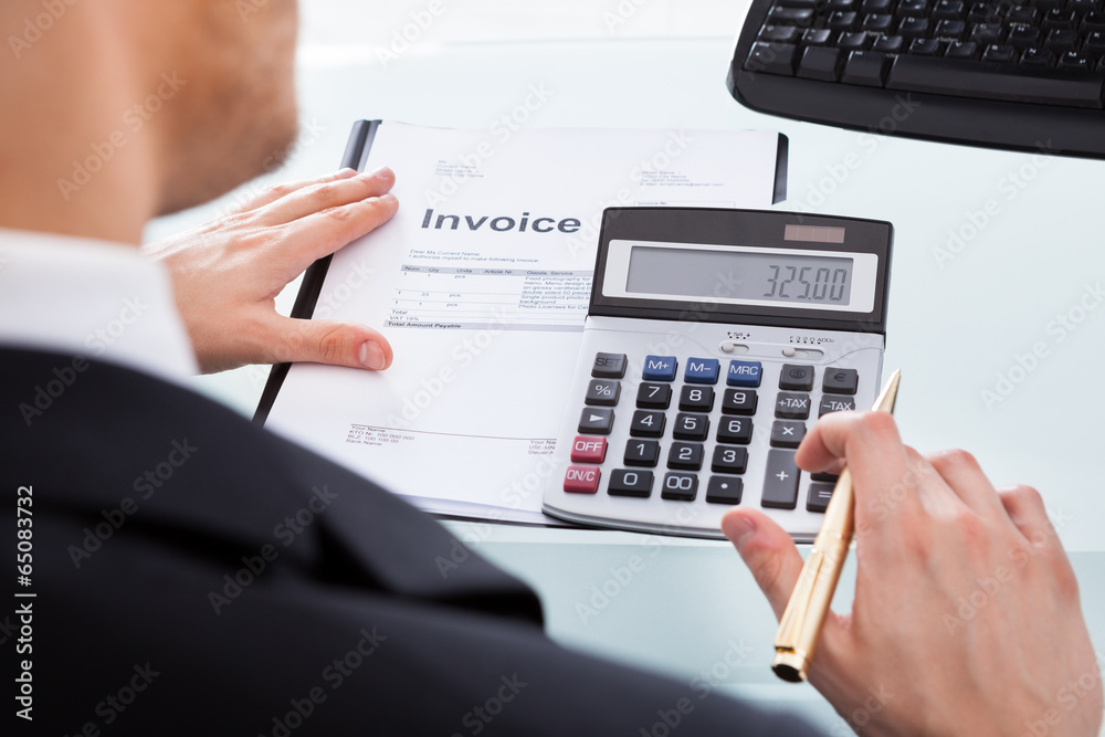 Businessman Calculating Invoice At Office Desk Businessman Calculating Invoice At Office Desk