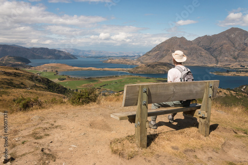 walker resting on wooden bench above lake Wanaka