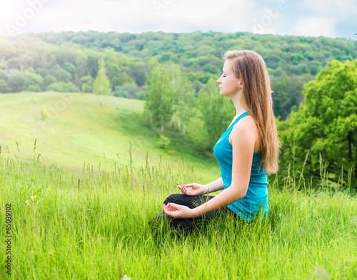 Girl relaxing on green grass. Happy woman sitting on the hill. photo