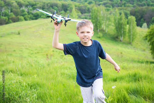 Happy kid playing with airplane. Beautiful nature background.