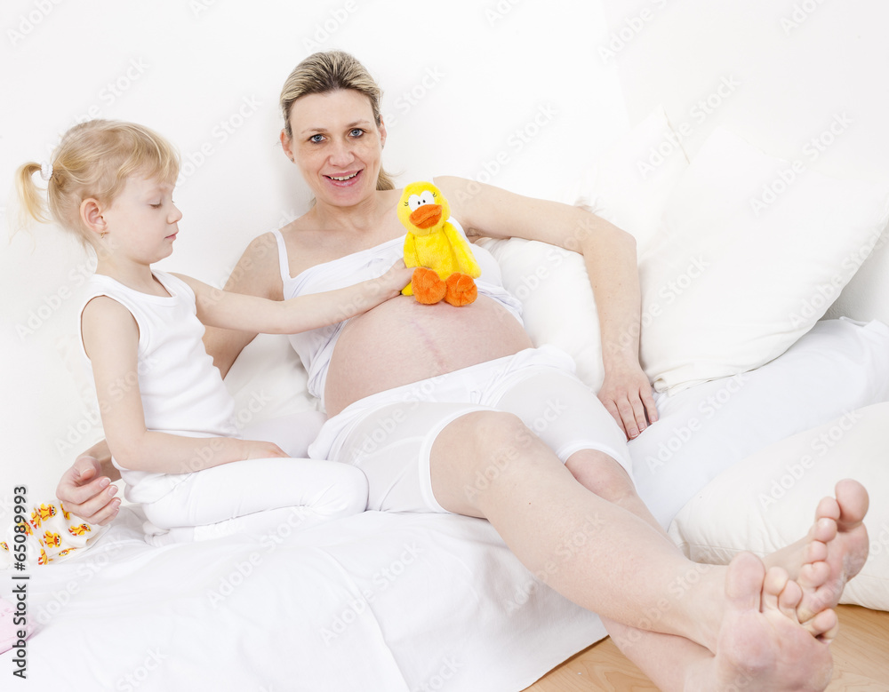 little girl and her pregnant mother with a toy for a baby little girl and her pregnant mother with a toy for a baby
