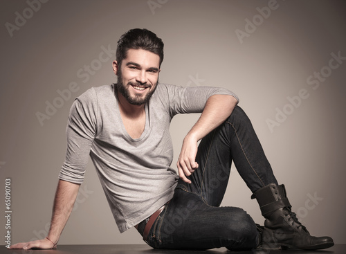 happy young man sits on the floor and smiles