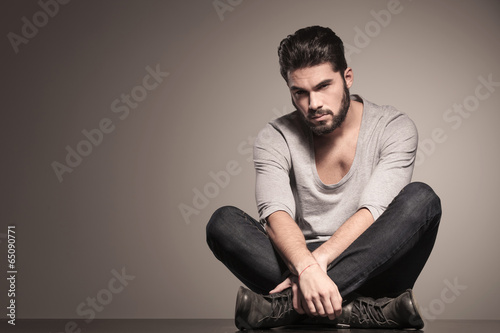 serious bearded fashion man sits in yoga position