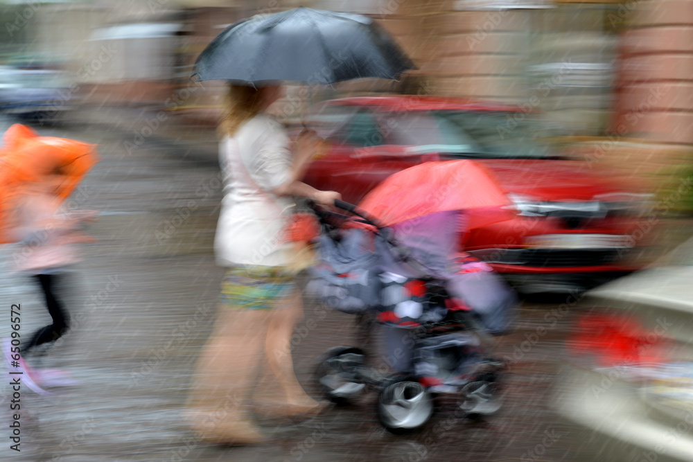 Fototapeta premium Mother walks with the child in the stroller on a rainy day