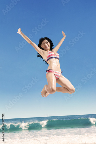 Excited woman jumping high at beach