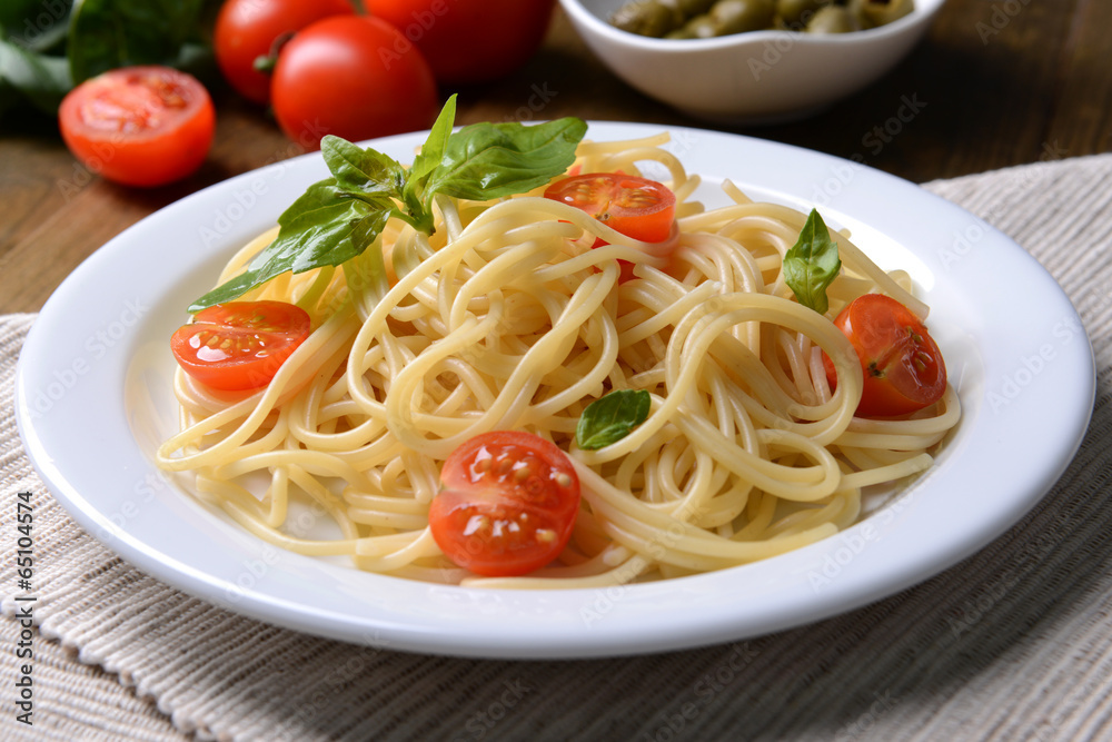 Delicious spaghetti with tomatoes on plate on table close-up Delicious spaghetti with tomatoes on plate on table close-up