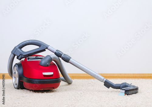 Red vacuum cleaner in empty room. photo