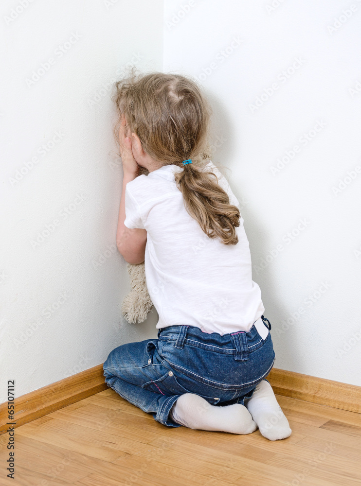 Fototapeta premium Little girl crying in the corner. Domestic violence concept.