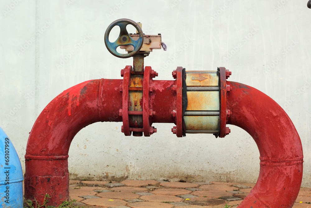 red rusty metal industrial water pipes with a valve.