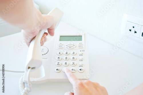 Photo of female hands dialing on white telephone
