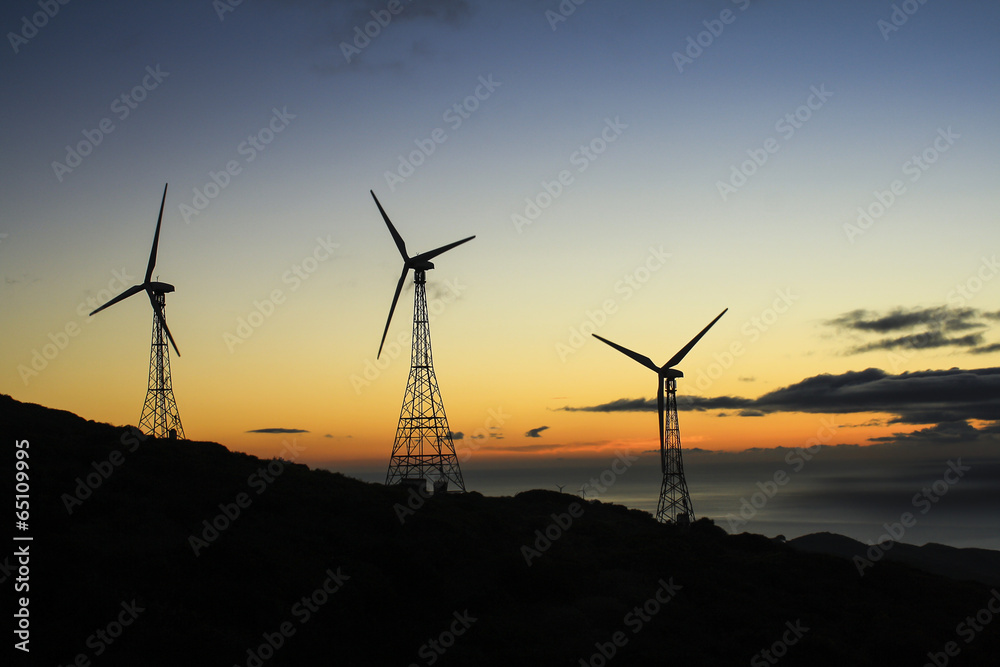 A group of three wind turbines at sunset in an eolic park A group of three wind turbines at sunset in an eolic park