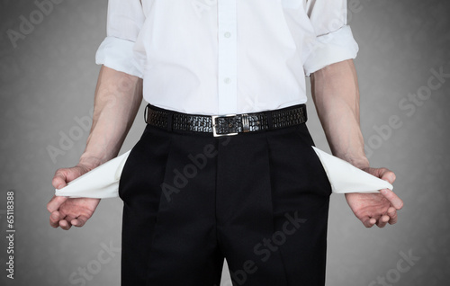 Businessman in white shirt shows empty pockets of his trousers